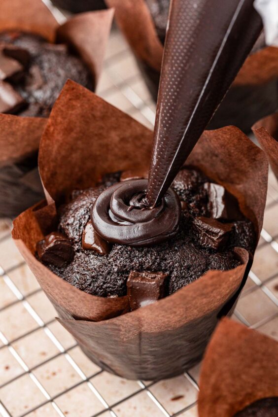 Hot fudge being piped into the center of an Olympic Chocolate Muffin.