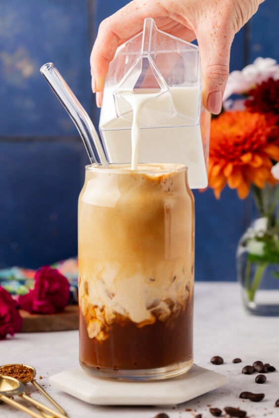 Milk being poured into a glass to make a Greek coffee.