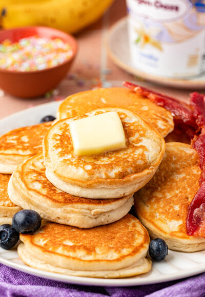 Ice cream pancakes on a plate with blueberries and bacon.