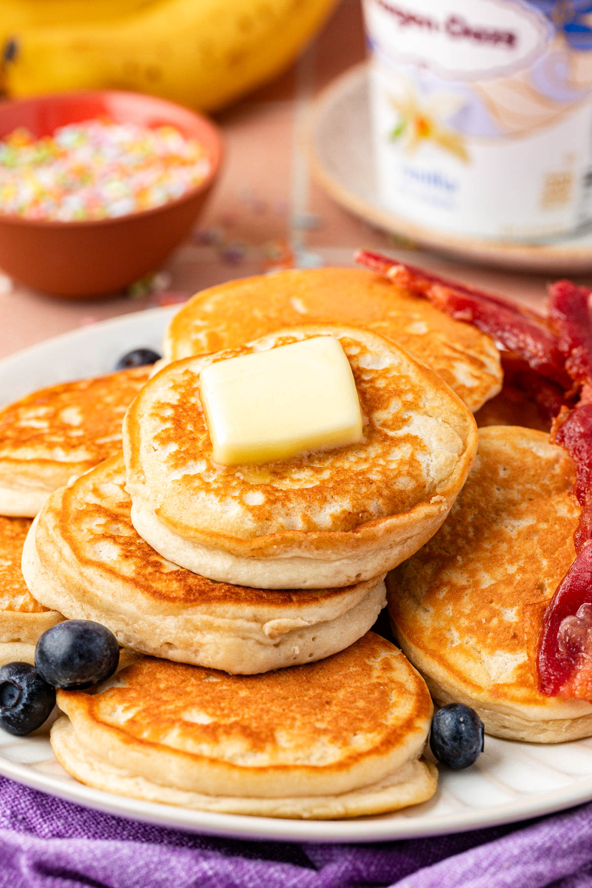 Ice cream pancakes on a plate with blueberries and bacon.