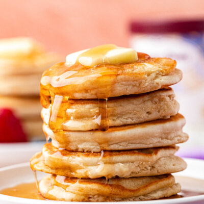 A stack of ice cream pancakes on a plate covered in syrup.