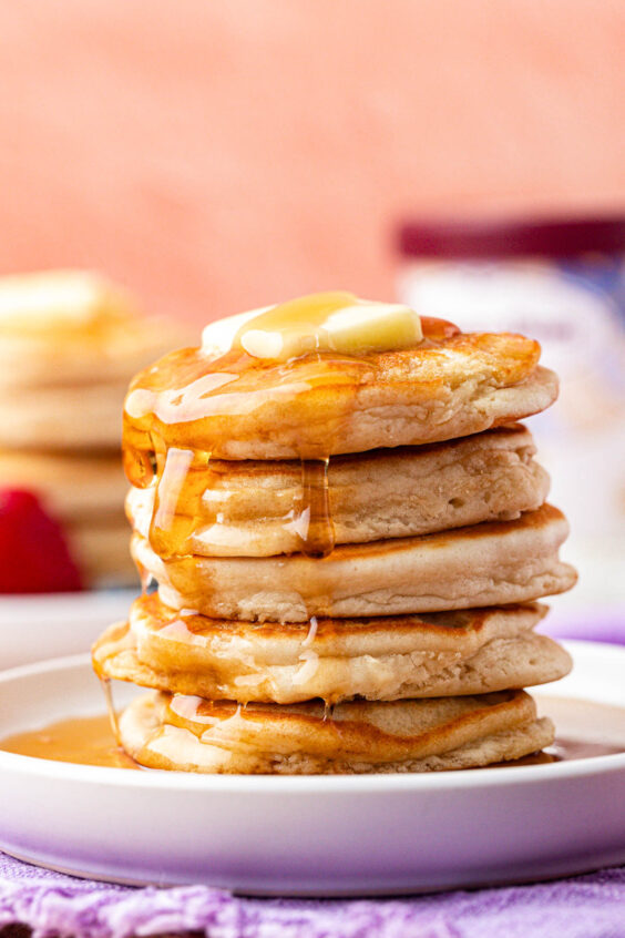 A stack of ice cream pancakes on a plate covered in syrup.