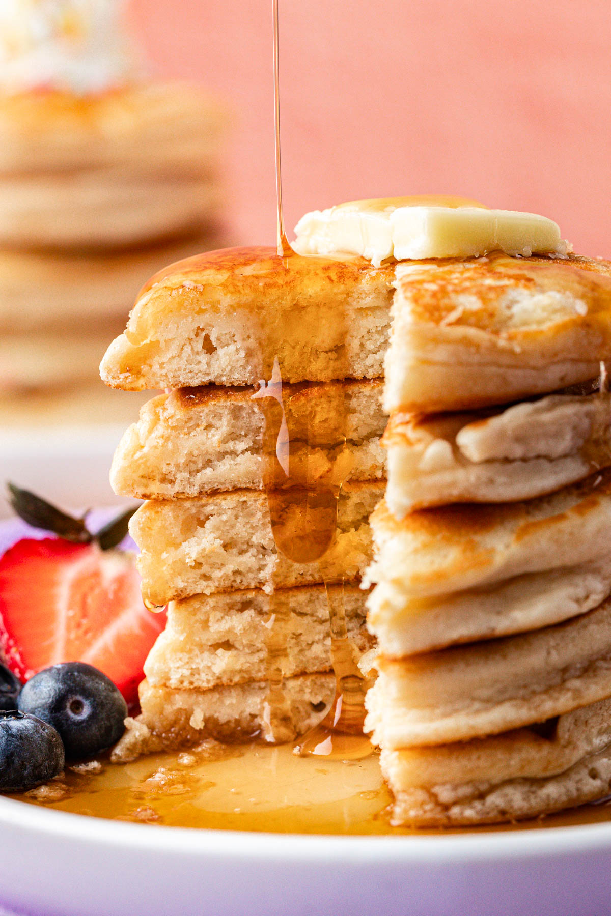 Syrup being poured on a stack of pancakes.