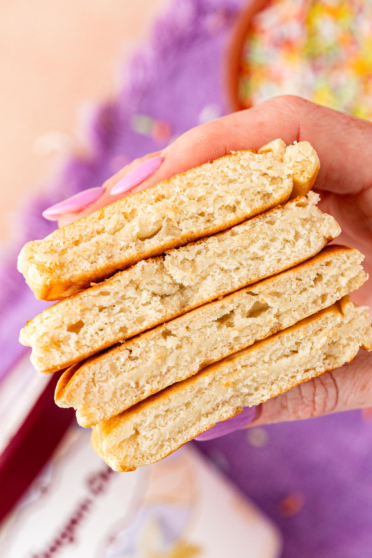 A woman's hand holding pancakes cut in half to show texture.