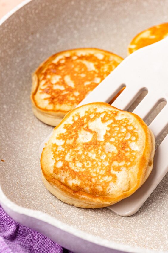 A spatula flipping a pancake in a pan.