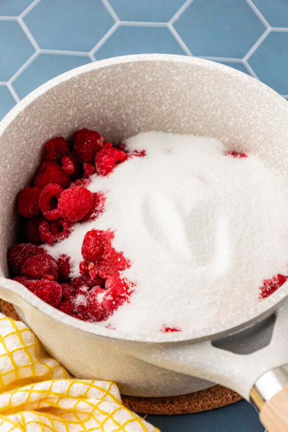 Raspberries and sugar in a small pot.