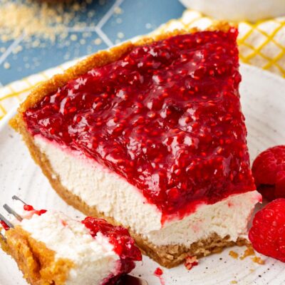 A slice of raspberry cream pie with a bite missing on a plate.