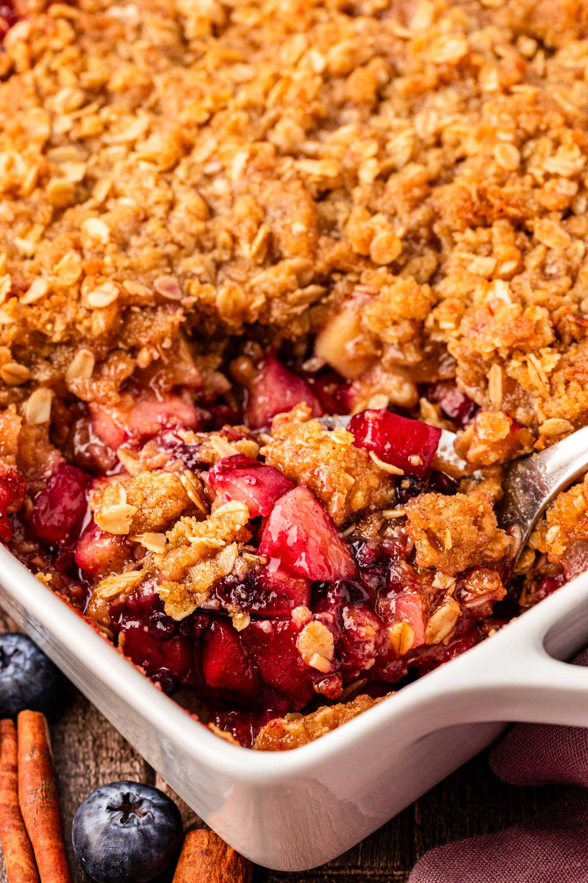 A spoon scooping blueberry apple crisp from a pan.