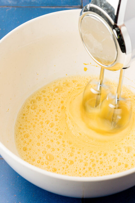 Eggs being beaten in a white bowl.