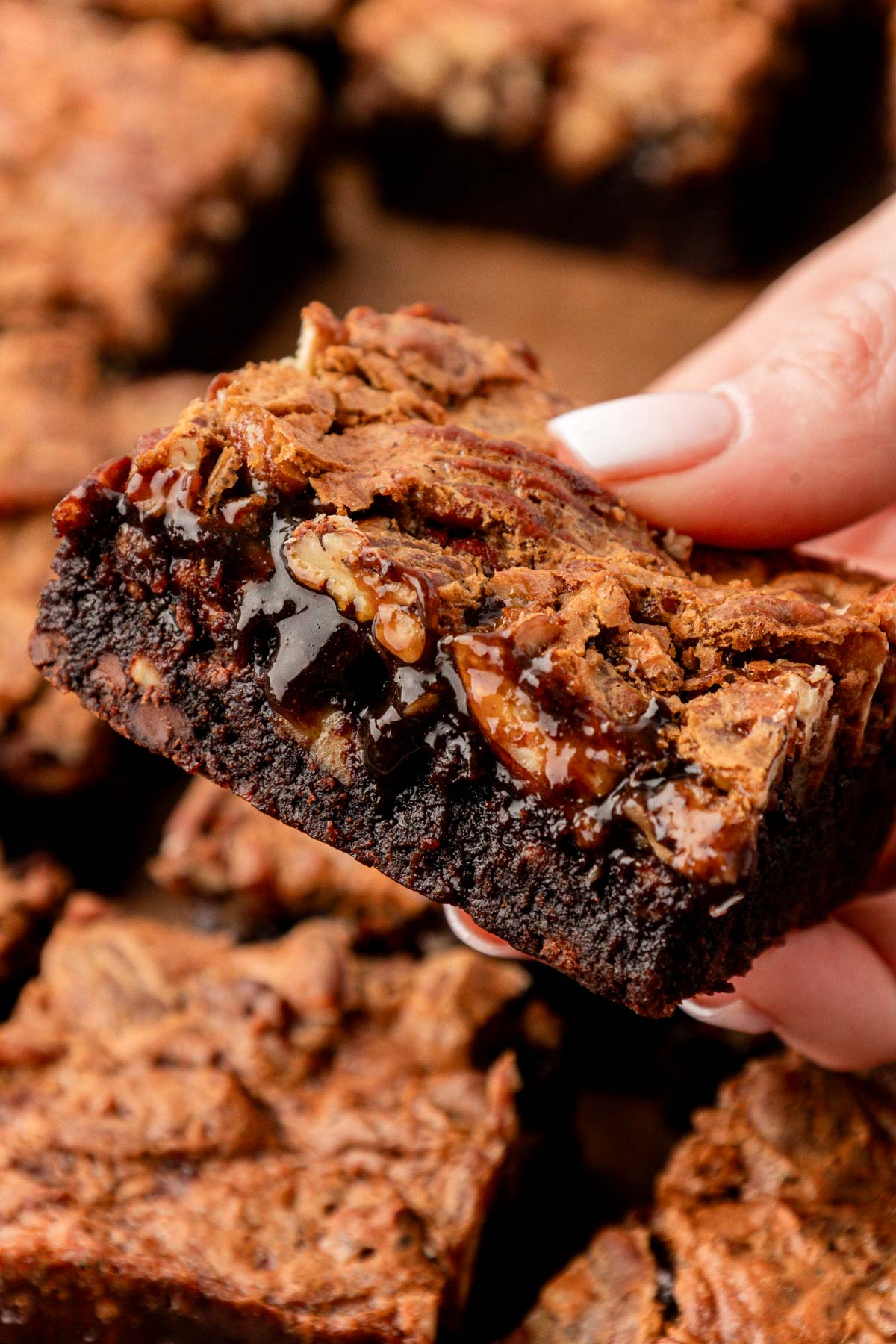 Close up of pecan pie brownies in a woman's hand.