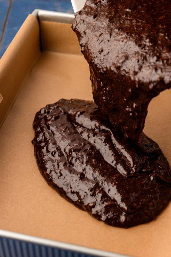 Brownie batter being poured into a baking pan.