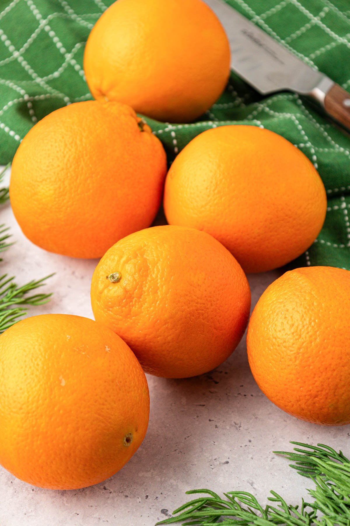 Oranges on a table with a green linen napkin.