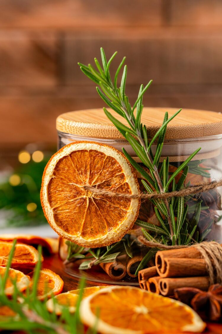 Dried orange slice and rosemary ties around a jar.