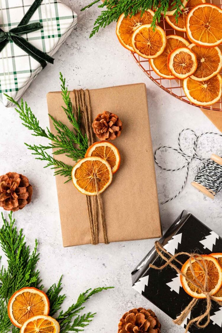 A book wrapped in brown paper and tied with twine and dried orange and pinecones.