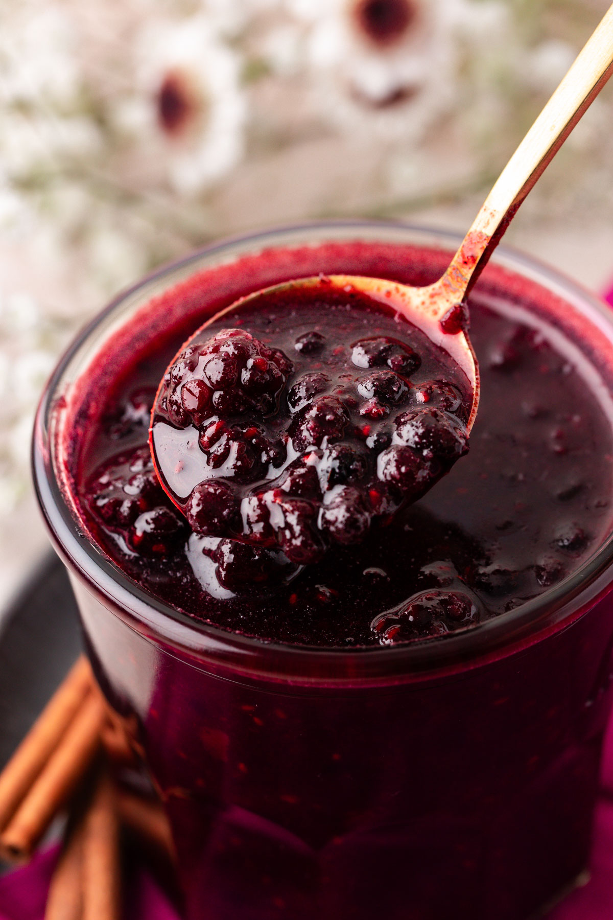 Close up of a jar of berry compote with a spoon lifting some out.