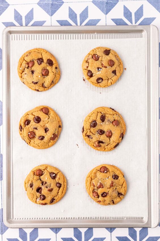 Bakery style chocolate chip cookies on a parchment lined baking pan.