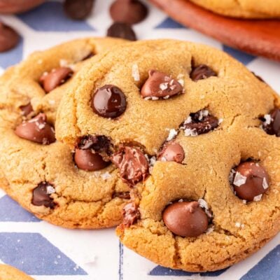 Close up of chocolate chip cookies on a table, one is missing a bite.