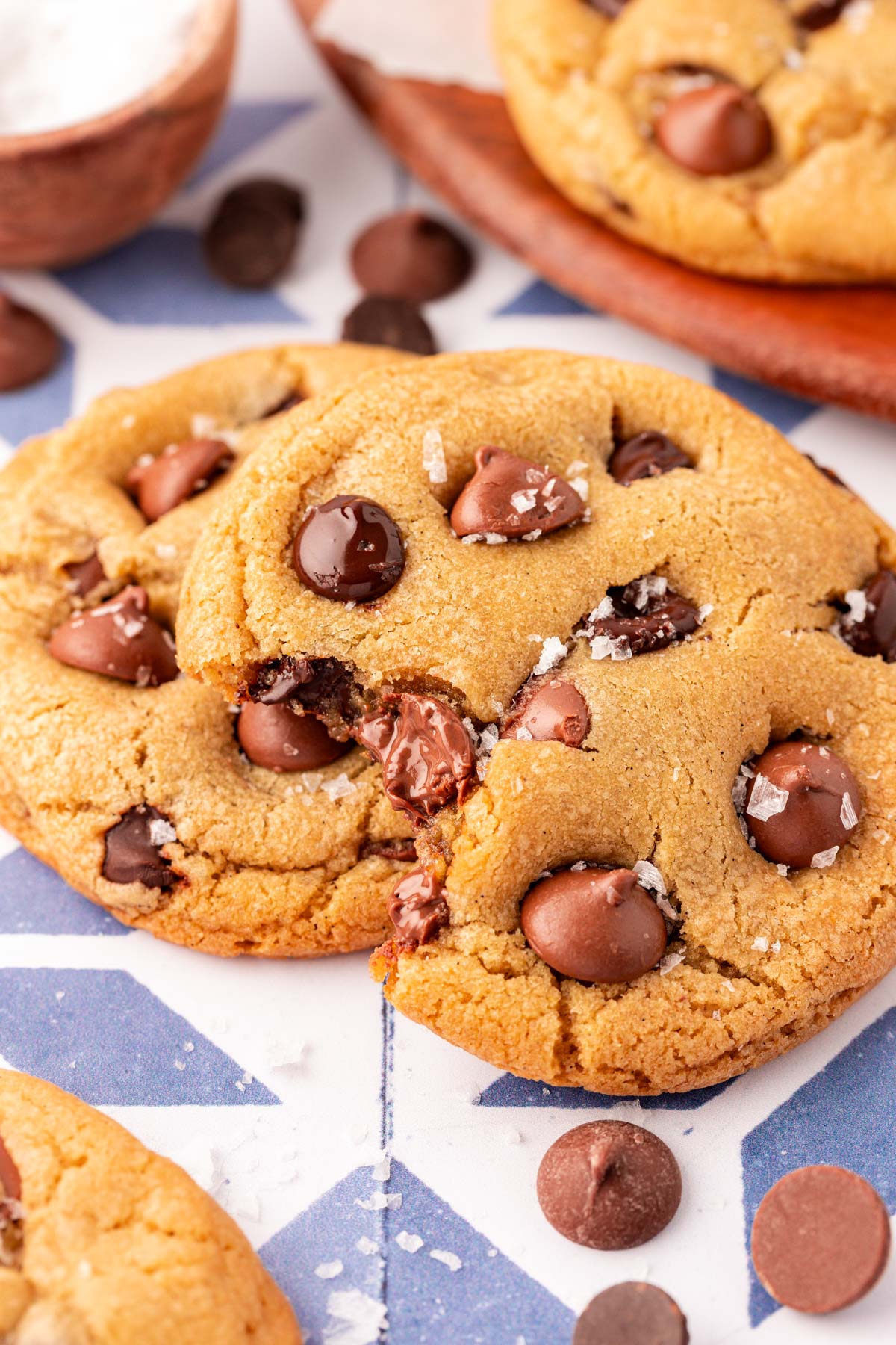 Close up of chocolate chip cookies on a table, one is missing a bite.