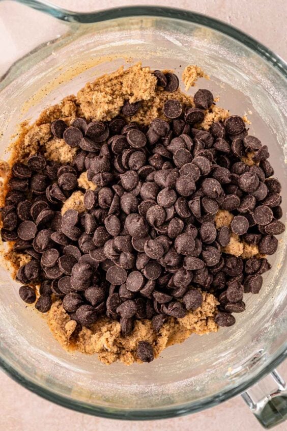 Chocolate Chips being added to a mixing bowl of cookie dough.