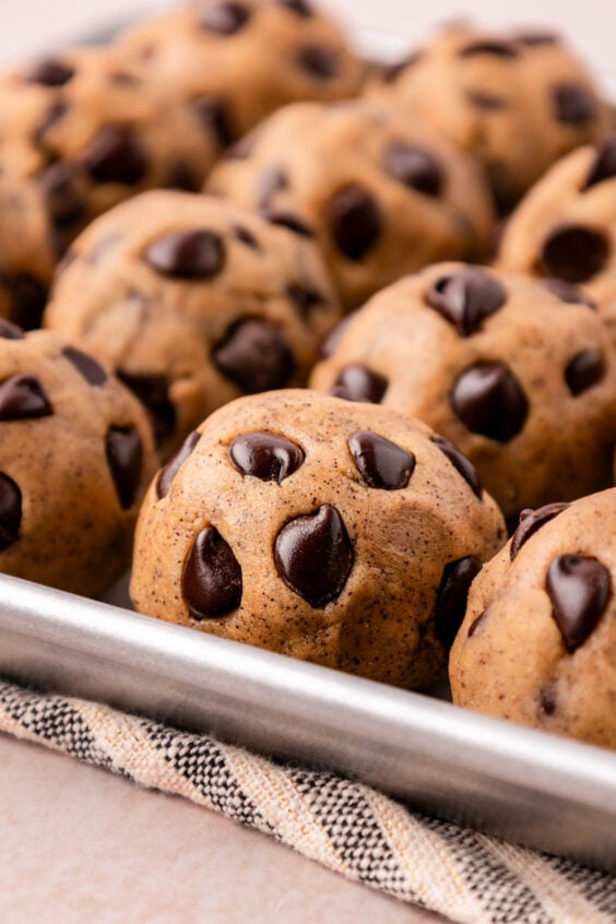 Close up of chocolate chip cookie dough balls on a sheet pan.