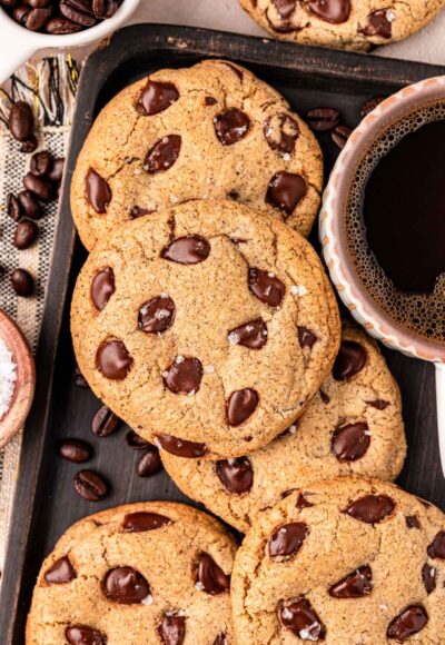 Overhead photo of Espresso Chocolate Chip Cookies on a cookie sheet with a mug of coffee.