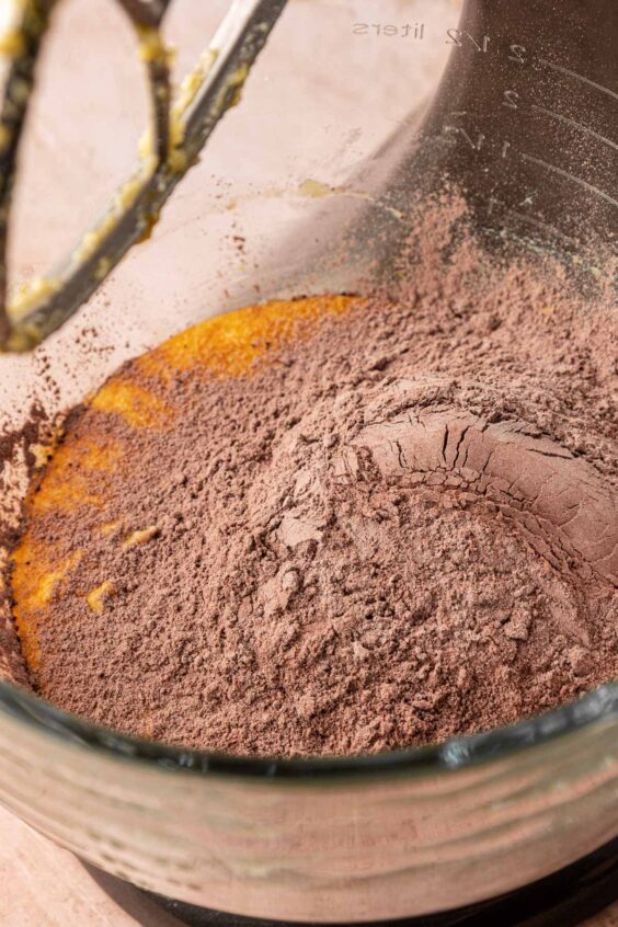 Dry ingredients being added to wet ingredients in a mixing bowl to make cookie dough.