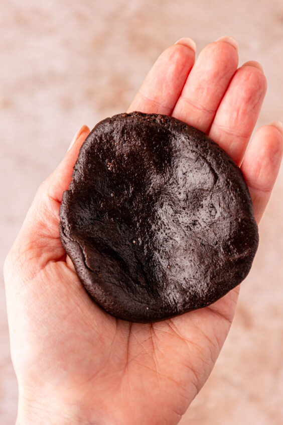 A circle of chocolate cookie dough in a woman's hand.