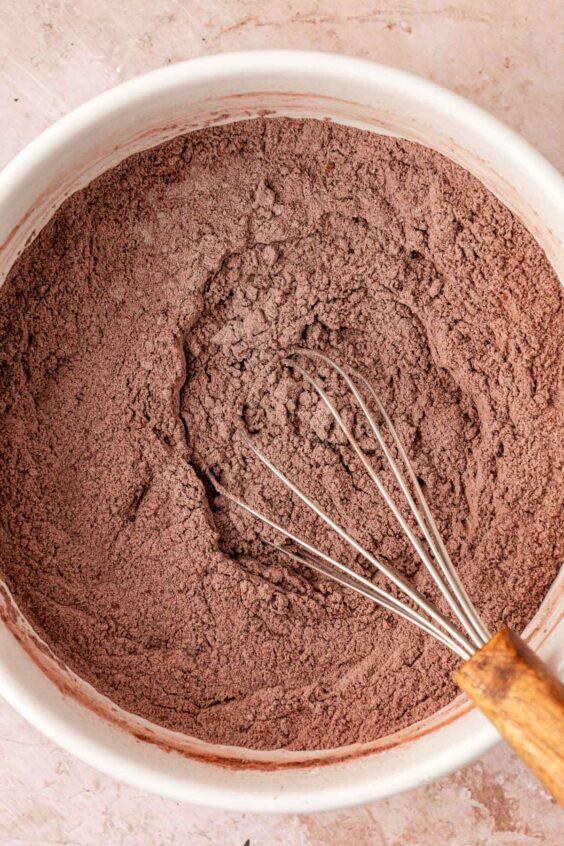 Dry ingredients for chocolate cookies being whisked in a white bowl.