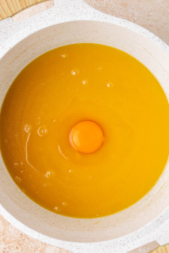 An egg in a pot with melted butter and sugar.