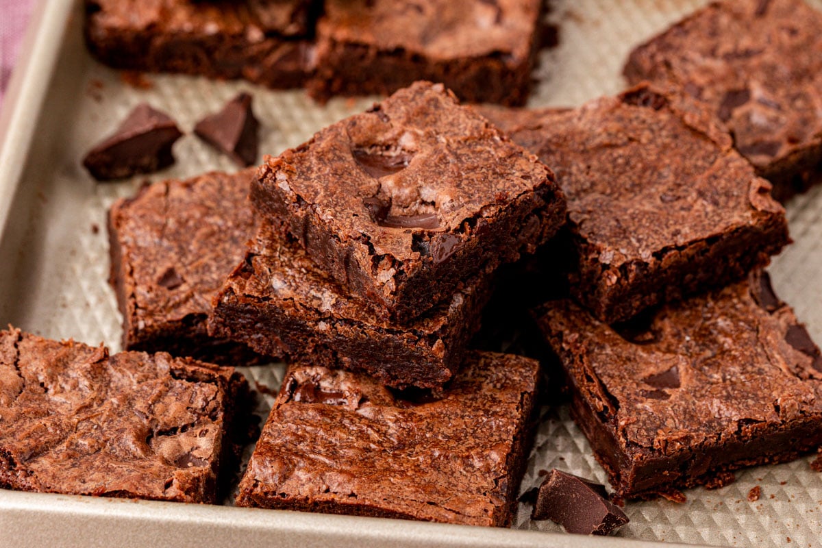 Sheet pan brownies cut up and stacked on a sheet pan.