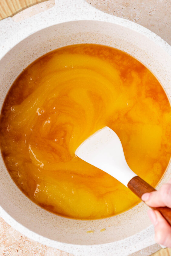 Vanilla being stirred into butter and sugar in a saucepan.