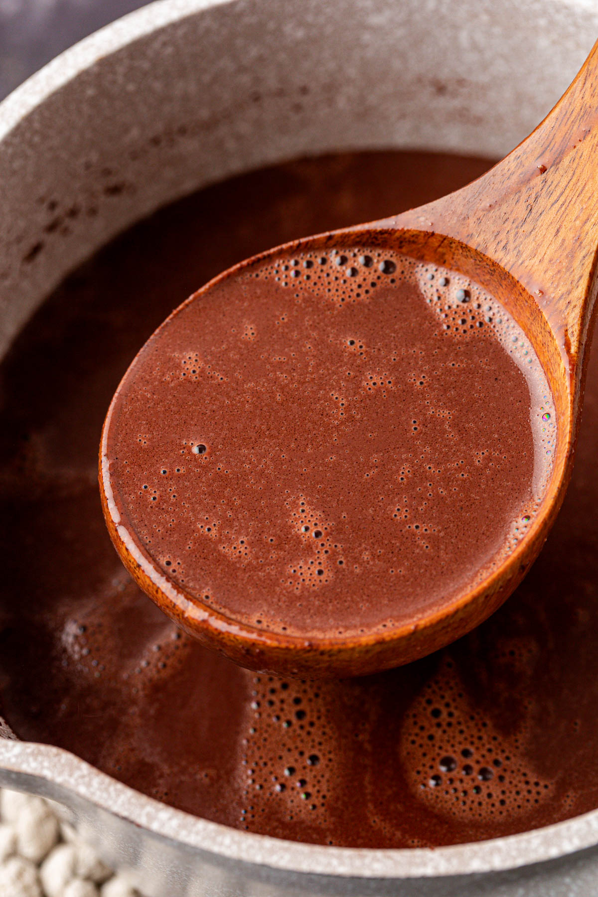 Hot Chocolate in a wooden ladle being removed from a pot.