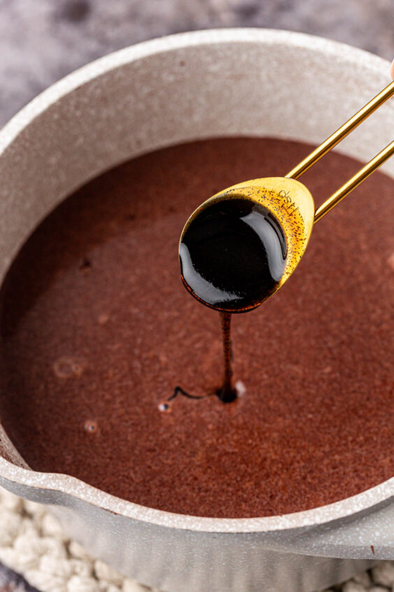 Vanilla bean paste being added to a pot of chocolate.