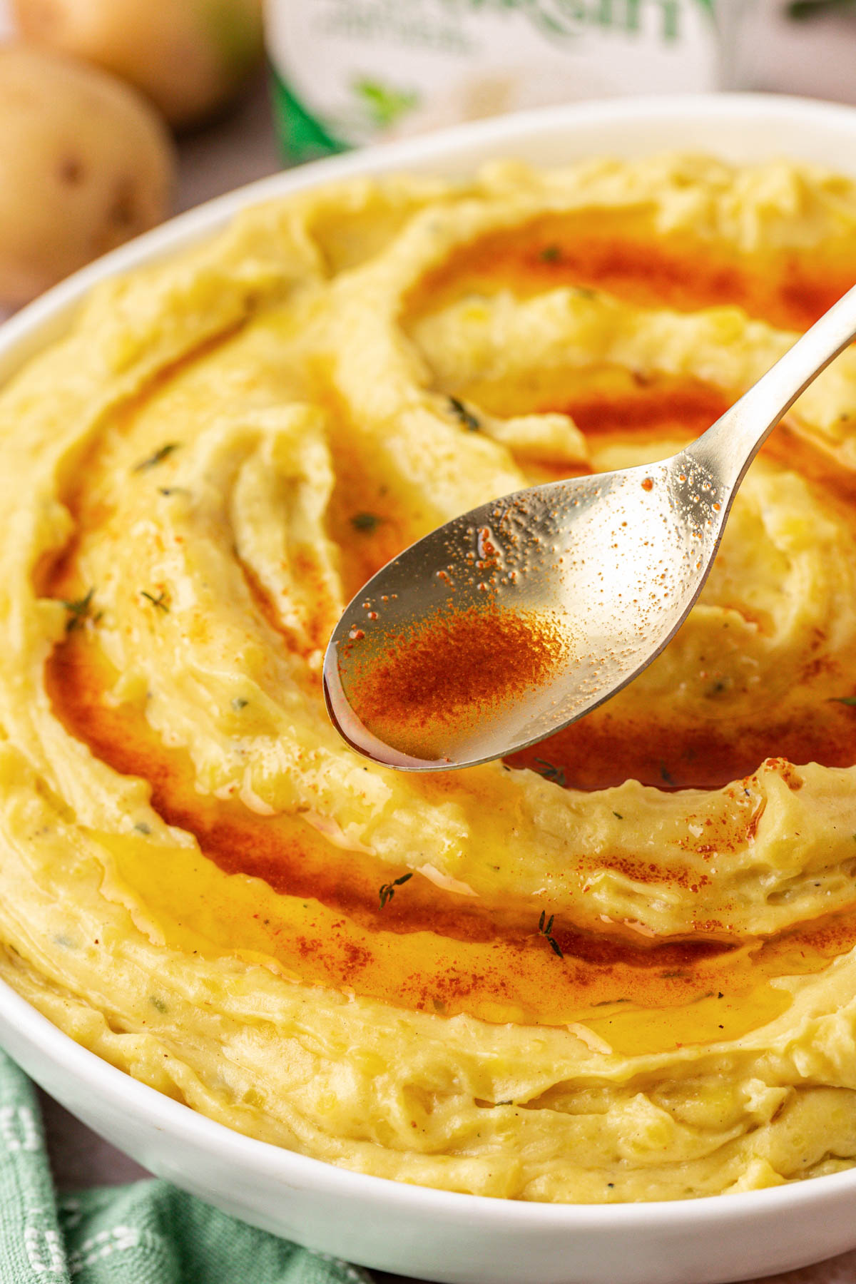 Brown butter being poured over the top of a bowl of mashed potatoes.