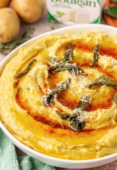 Close up of a bowl of mashed potatoes with brown butter on top.