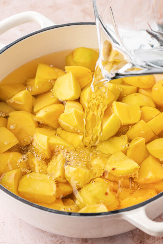 Water being poured into a pot with potatoes.