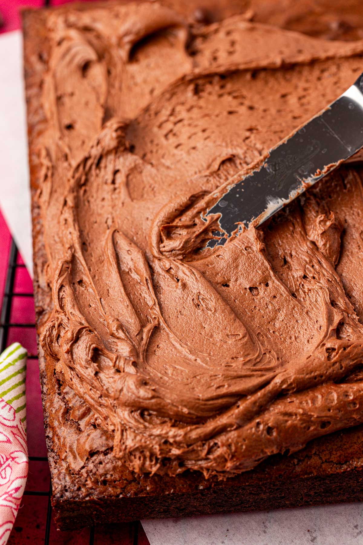 Brownies being frosted with chocolate frosting.