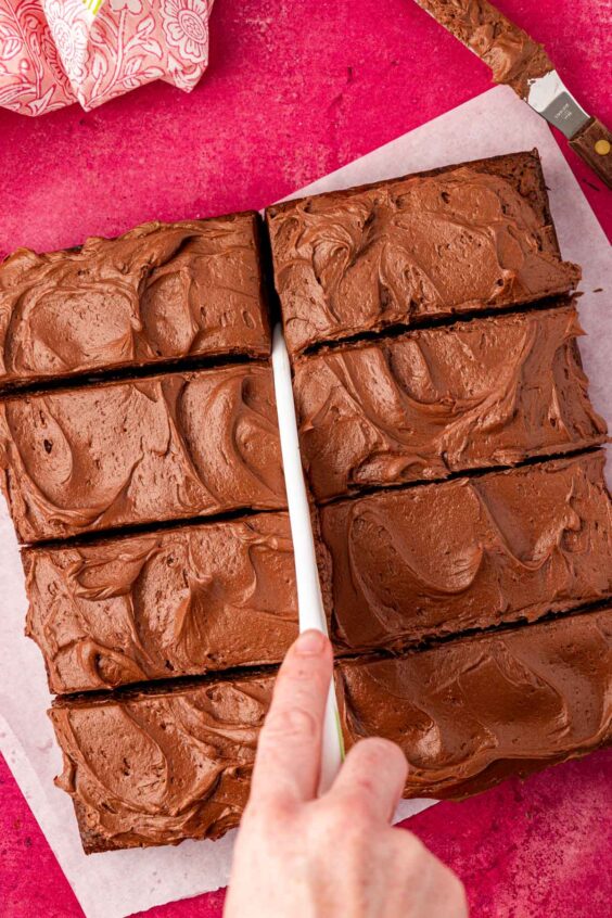 Brownies being cut with a large knife.