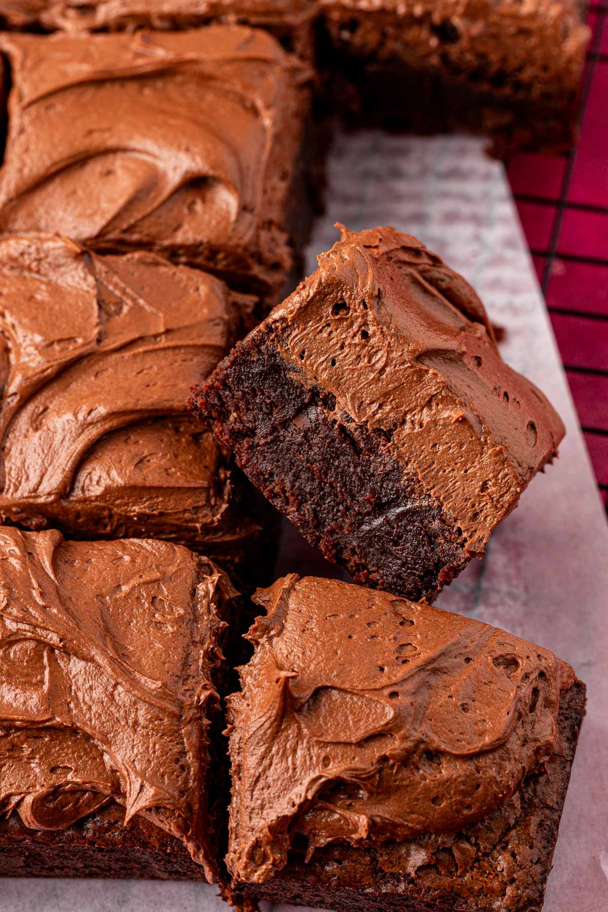 Close up of chocolate frosted brownies cut up on a wire rack.