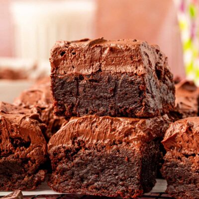 Close up of frosted brownies on a plate. Two stacked on top of each other in the front.