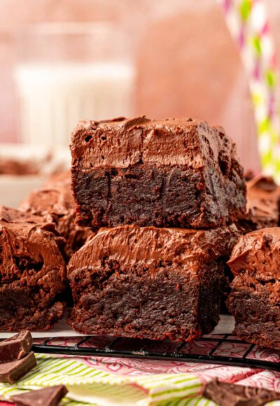 Close up of frosted brownies on a plate. Two stacked on top of each other in the front.