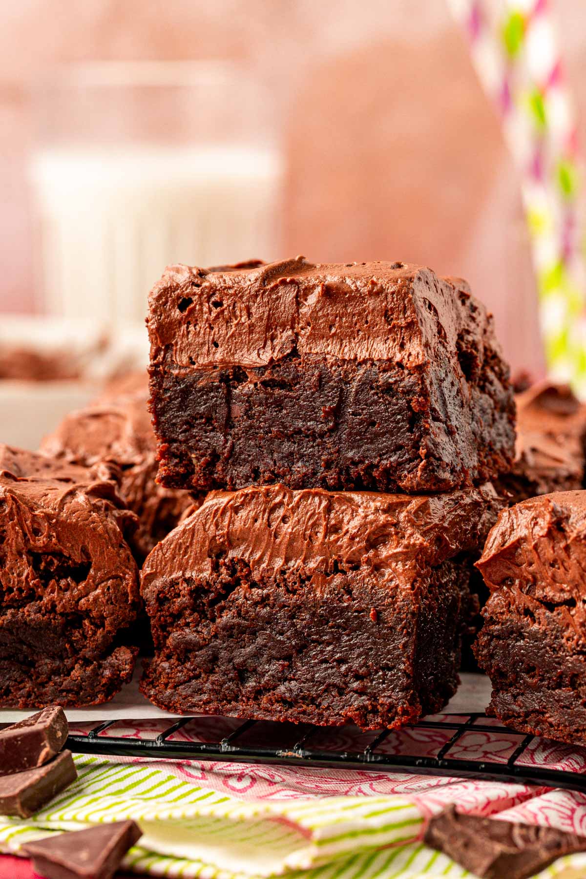 Close up of frosted brownies on a plate. Two stacked on top of each other in the front.