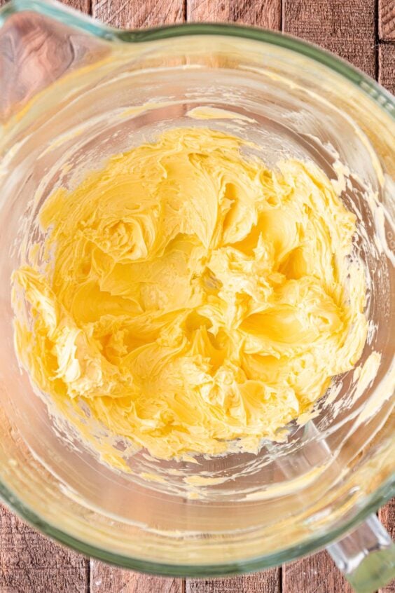 Butter being creamed in a glass mixing bowl.