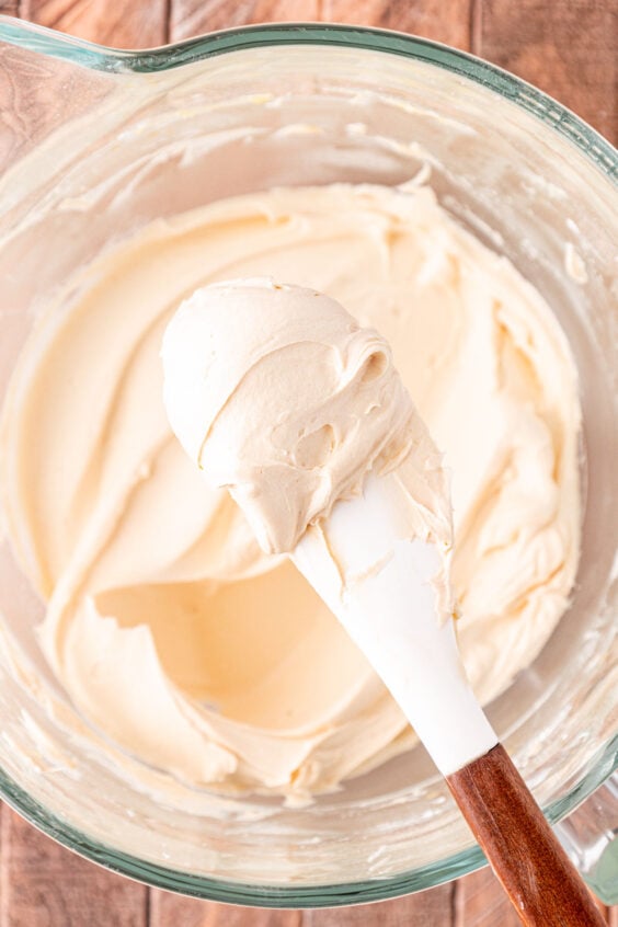 A spoon scooping Irish Cream frosting out of a mixing bowl.