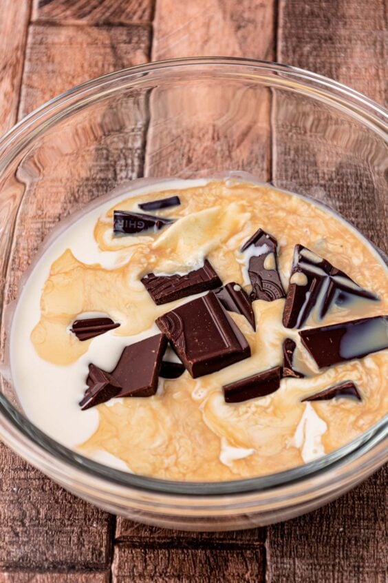 Heavy cream and chopped chocolate in a glass mixing bowl to make ganache.