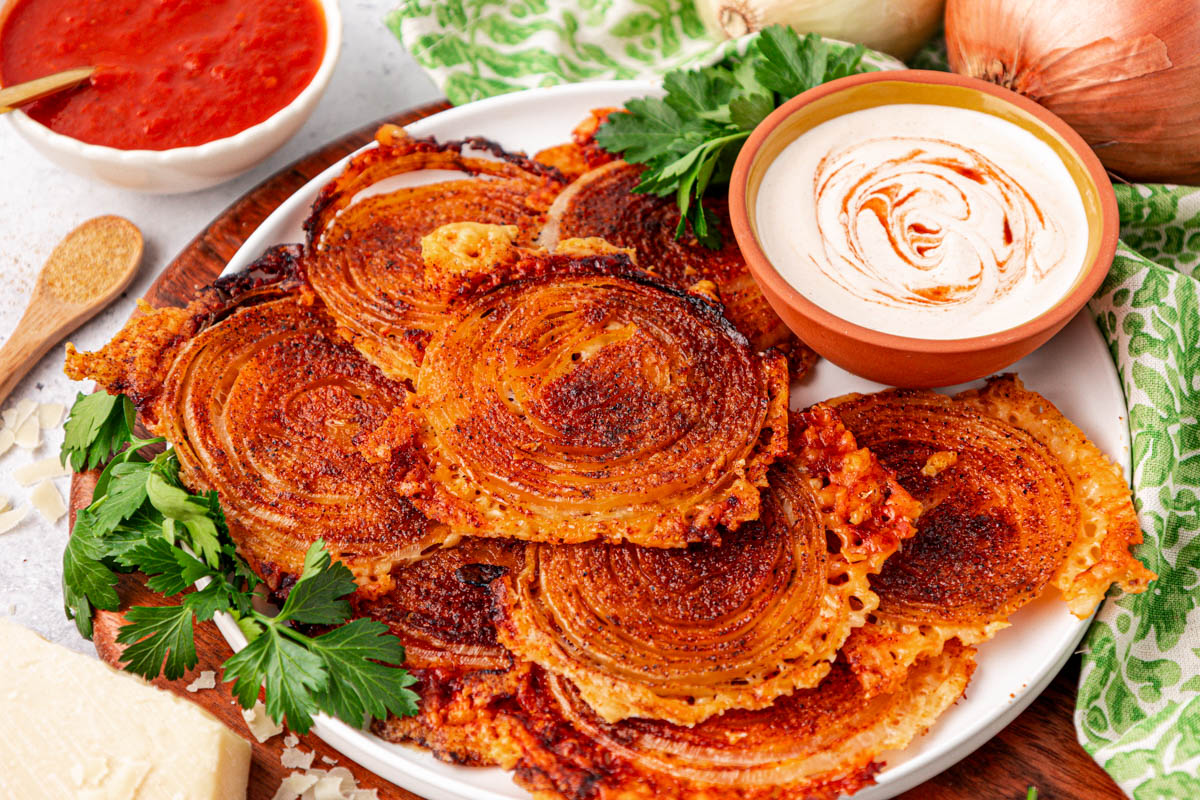 Onion ring chips on a white plate with dipping sauce.