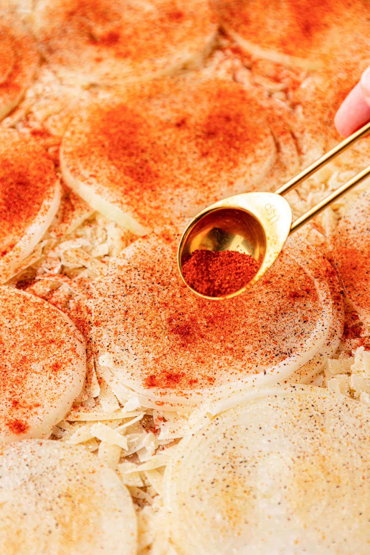 Spices being sprinkled on onion slices.